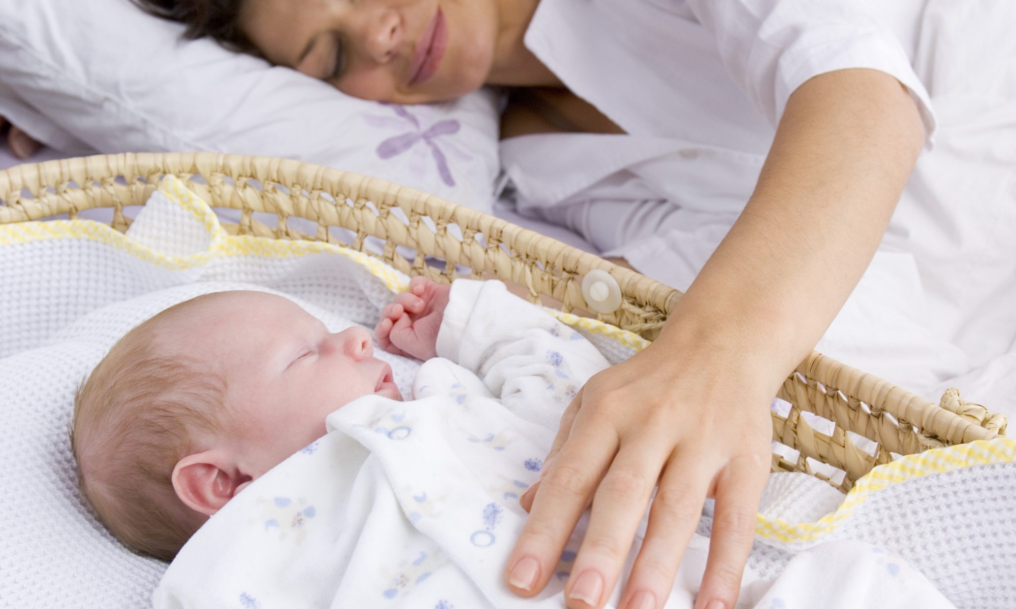 Mother reaching for baby in bassinet